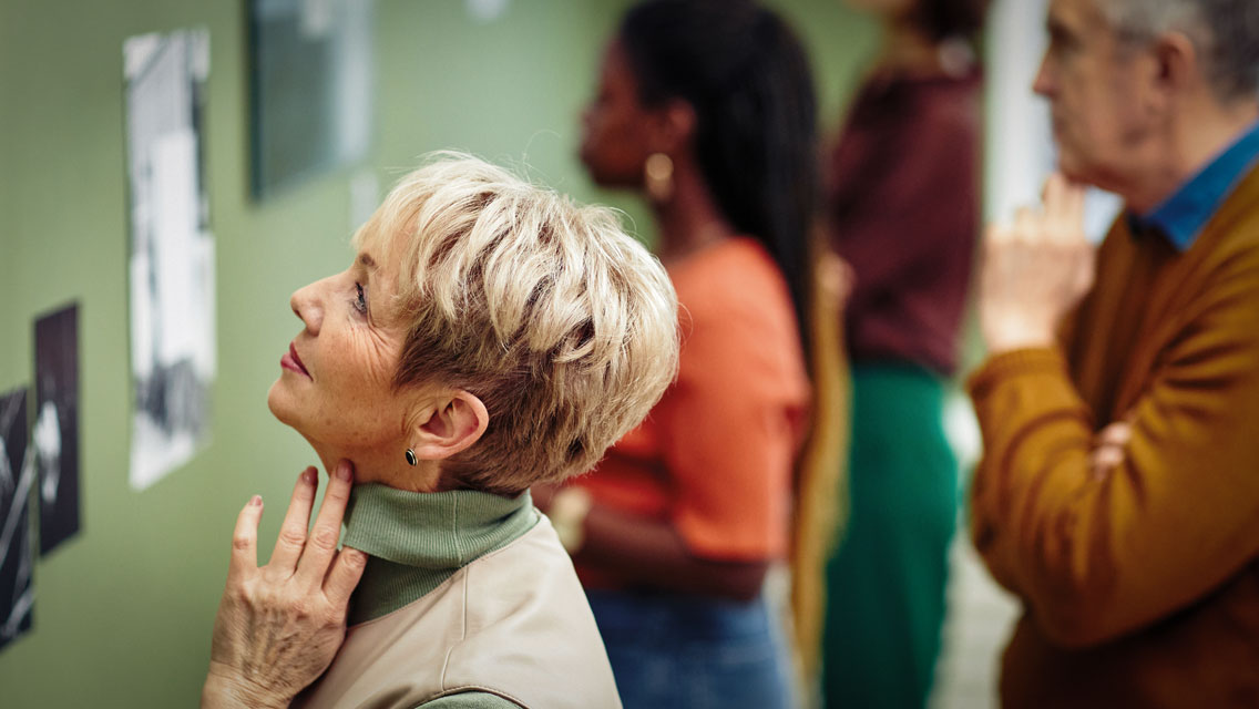 a senior woman looks at art