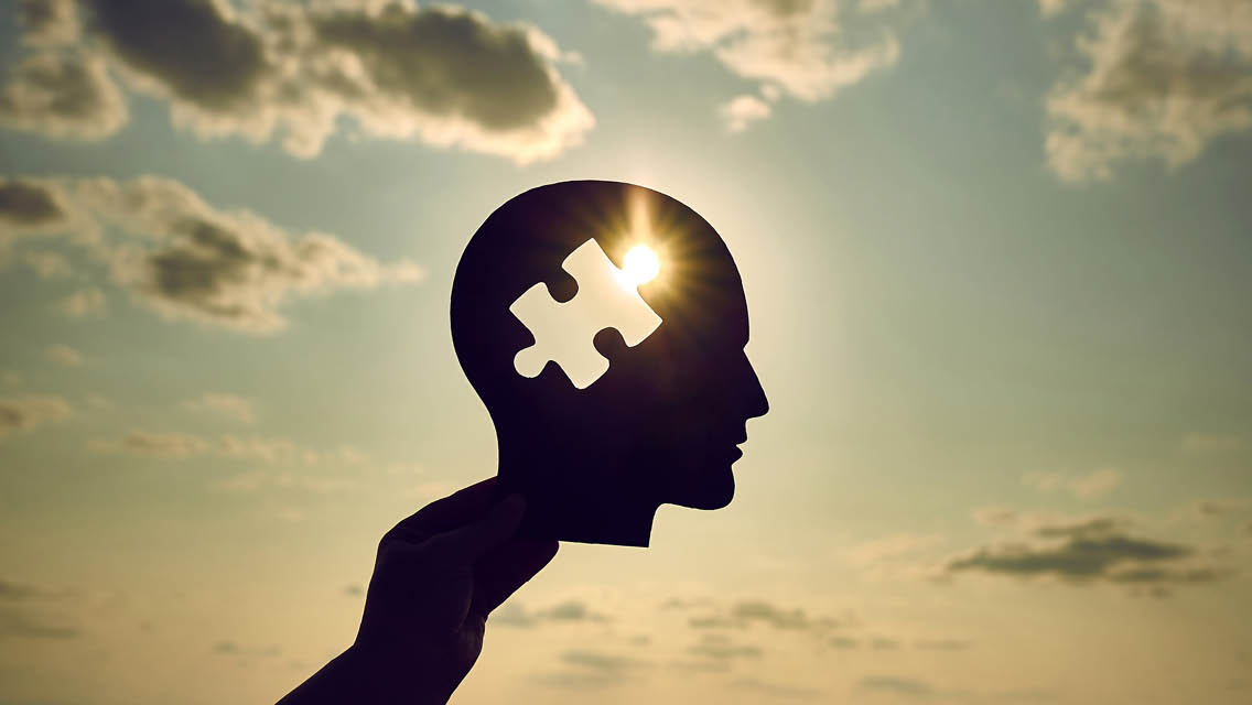 a puzzle piece cut out of a face shaped piece of paper