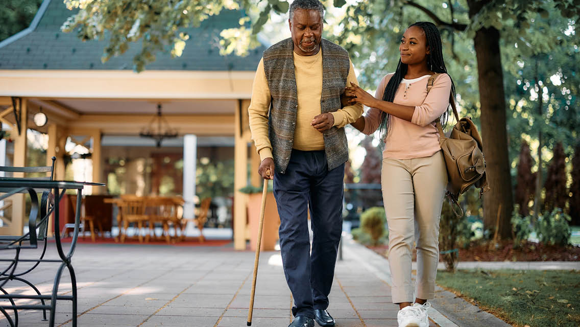 a young woman helps an elderly man walk