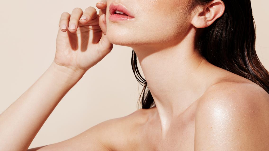 A close-up of a woman with bright, glowing skin.