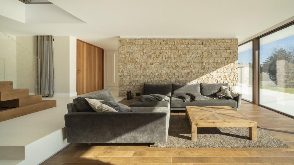 A clean living room space in a home with light shining in through the open windows.
