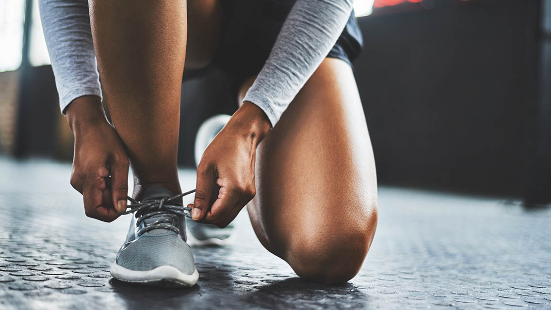 Woman tying tennis shoes.