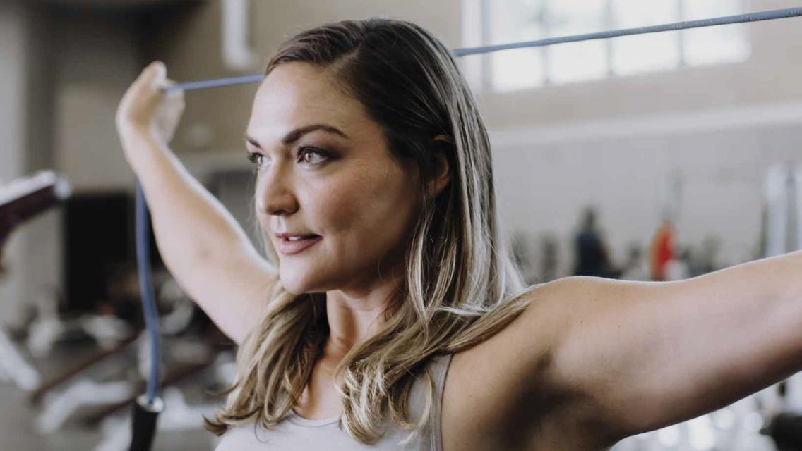 Lindsay Guentzel holding a resistance band behind her head.