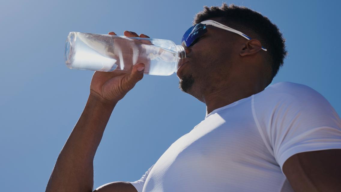 Person drinking water from a water bottle outdoors