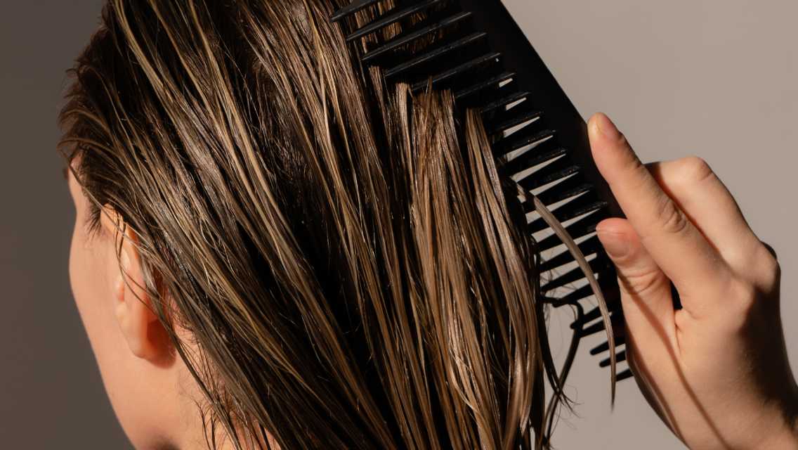 Back of a person's head while they are combing their hair