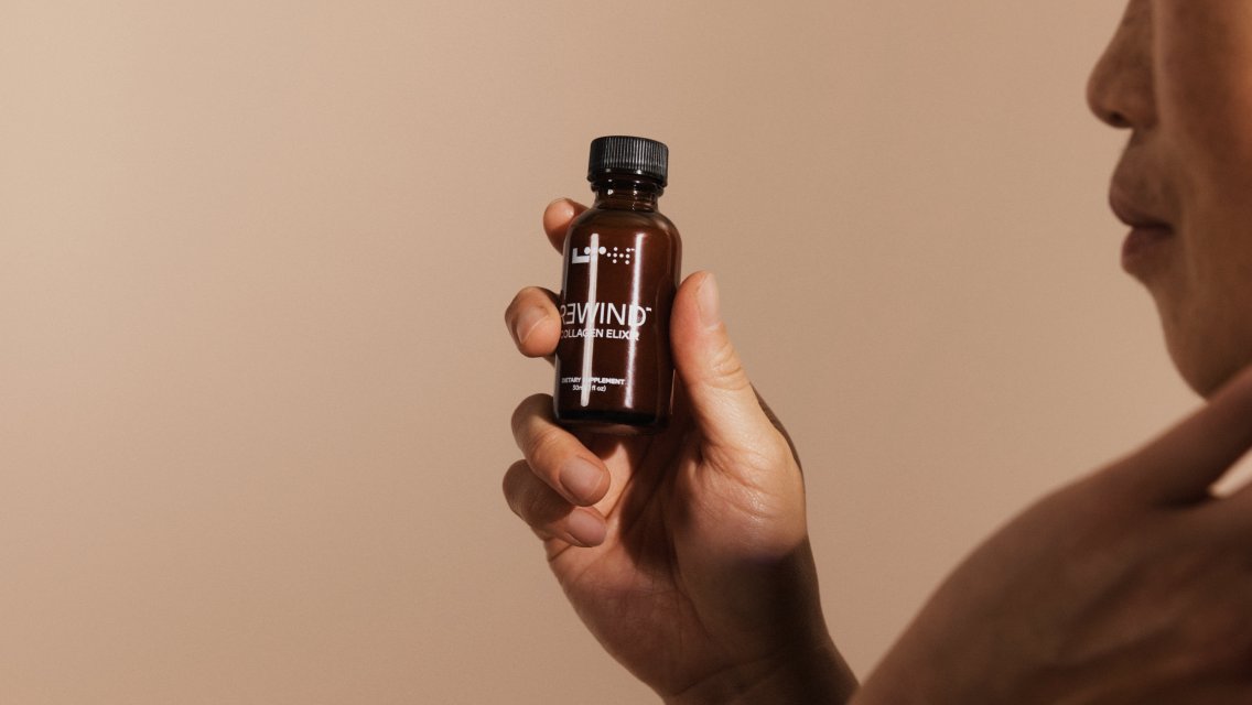 A woman holding a bottle of LTH Rewind Collagen Elixir