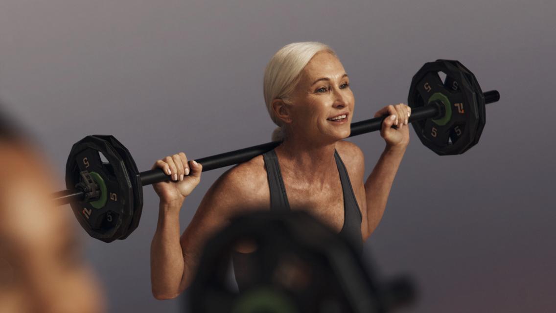 Person in a group fitness class doing a squat with a barbell on their back