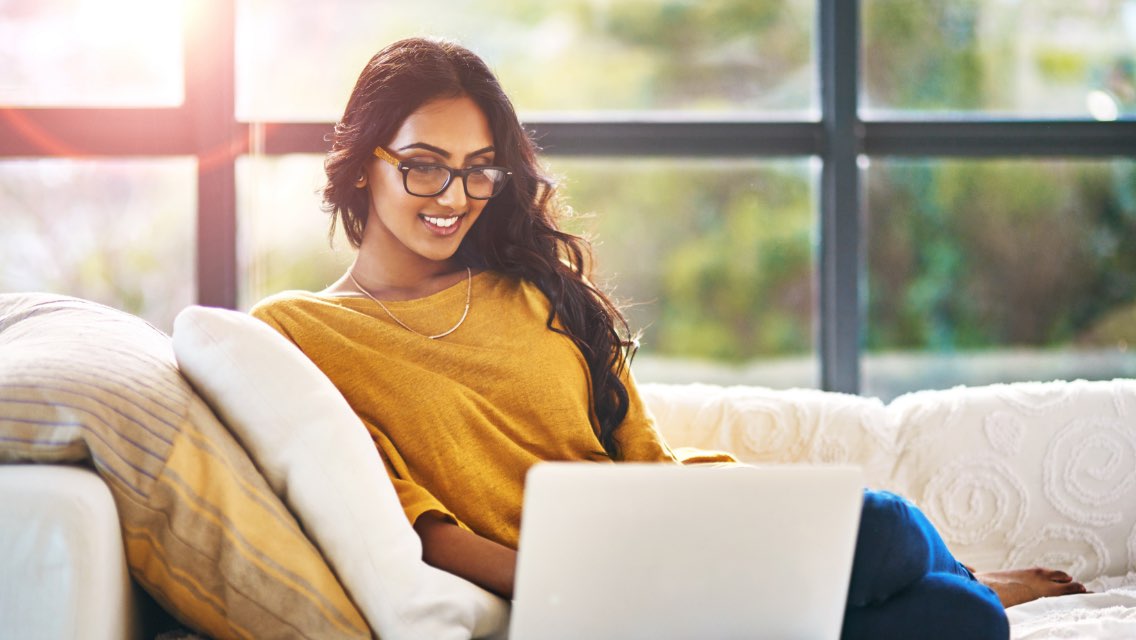 A woman sitting on a couch and using a laptop.