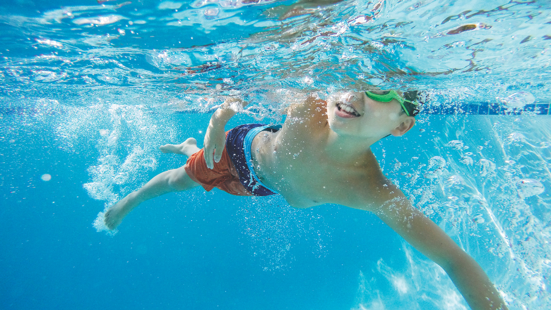A young boy swimming in a pool.