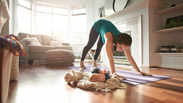 Woman doing down dog with new born next to her