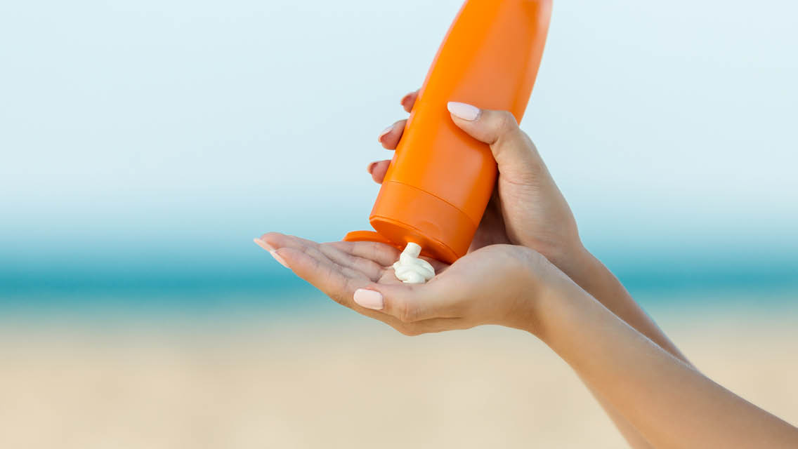 a pair of hands squeezes sunscreen