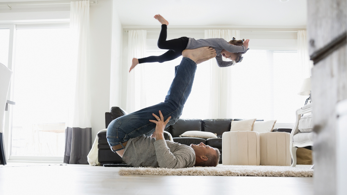 a man lays on the floor balancing his child on his feet