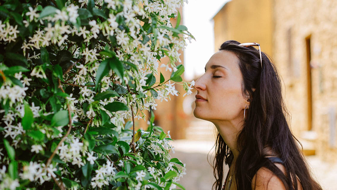 a woman stops to smell the jasmine.