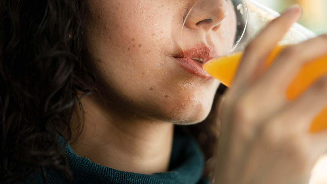 a woman drinks a glass of orange juice.