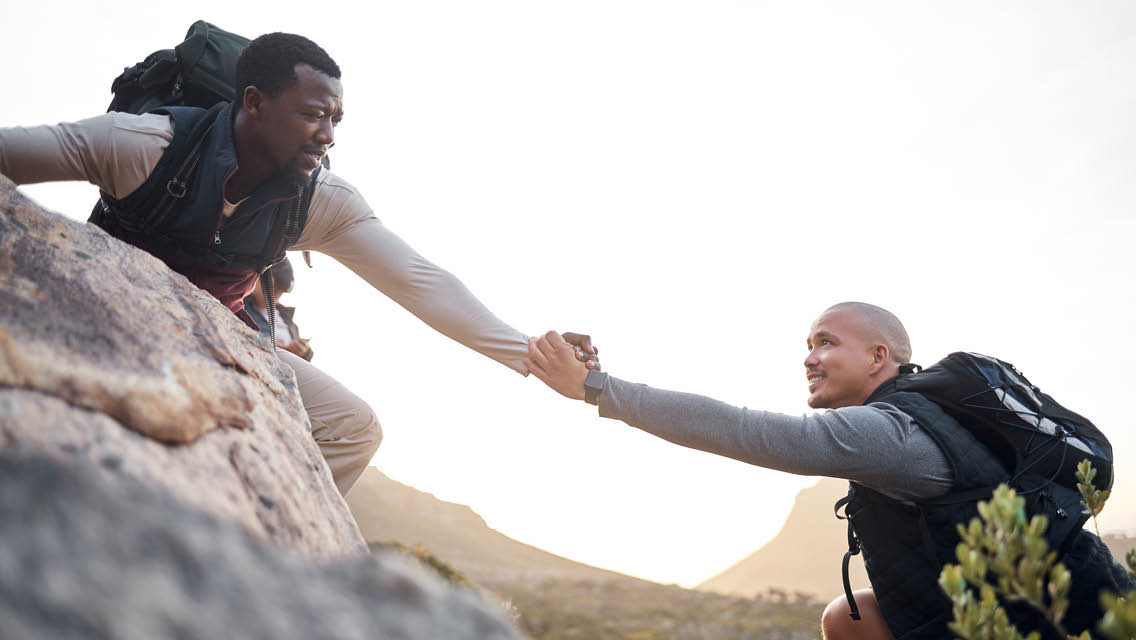 a hiker reaches out a had to the hiker behind him