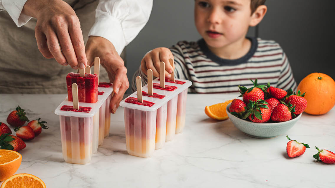 a little boy helps his mom make homemade popsicles