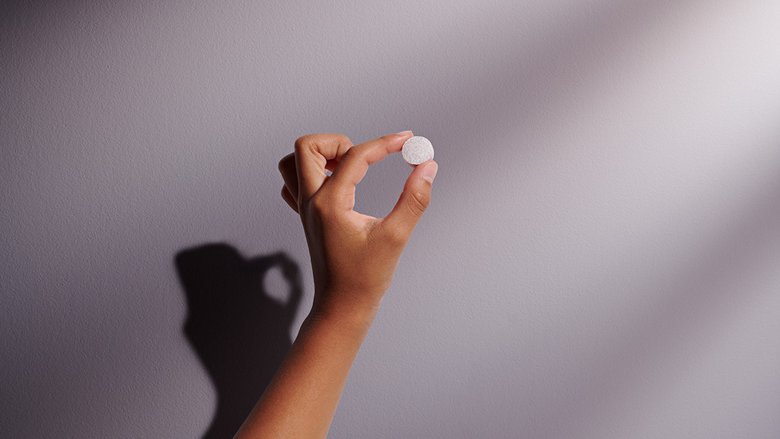 A child's hand holding one of the Life Time Immun-E-Z lozenges.