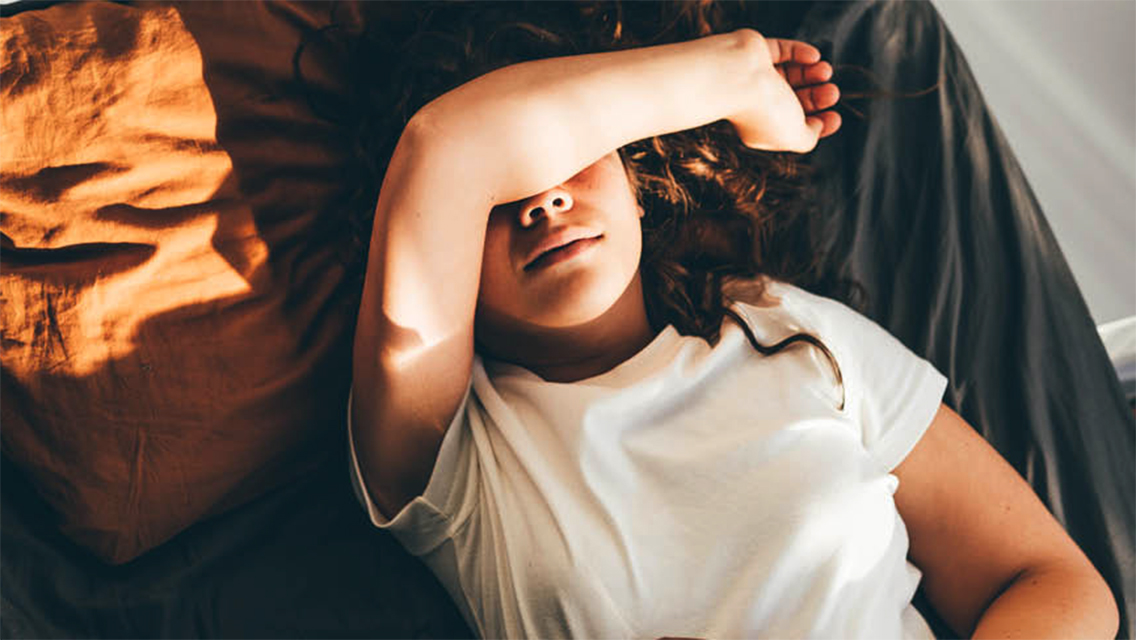 a woman lies down with an arm over her eyes