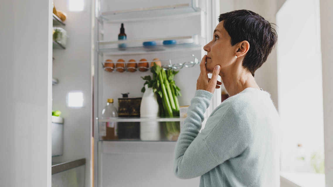 a woman looks in a refrigerator