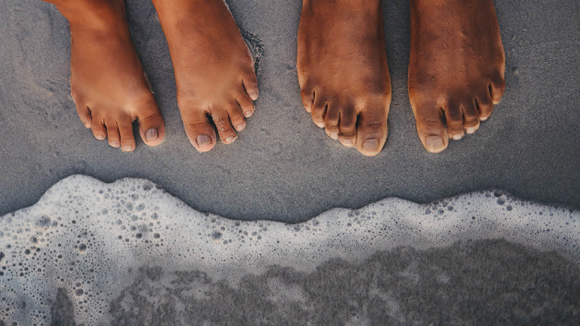 a pair of feet with waves washing up on to them