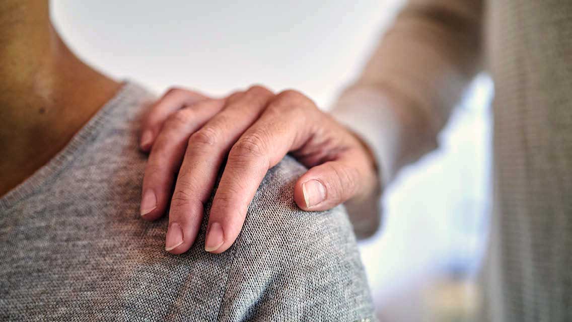 a person places a hand on a person's shoulder