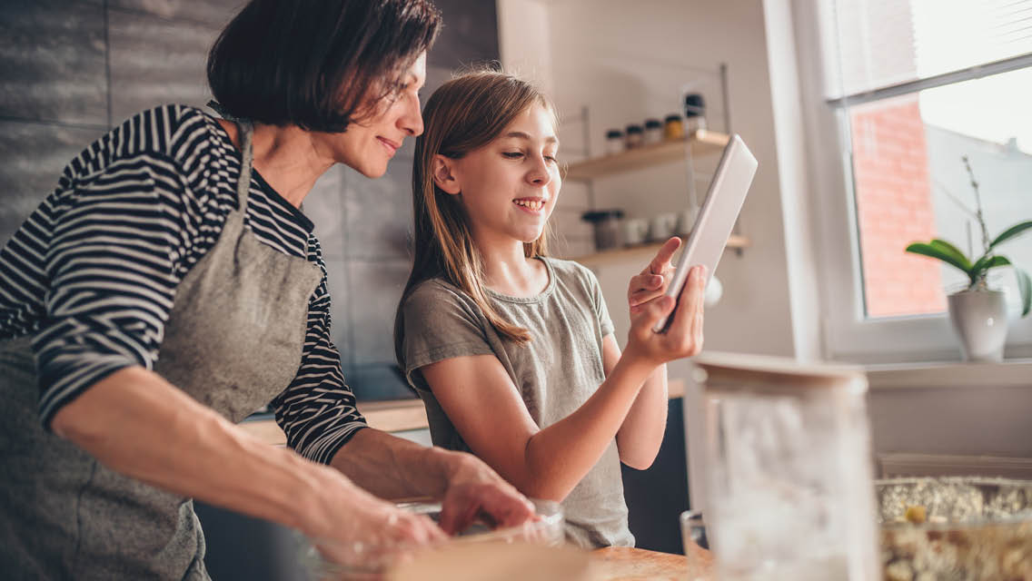 a mom and younger daughter cook in a kitchen