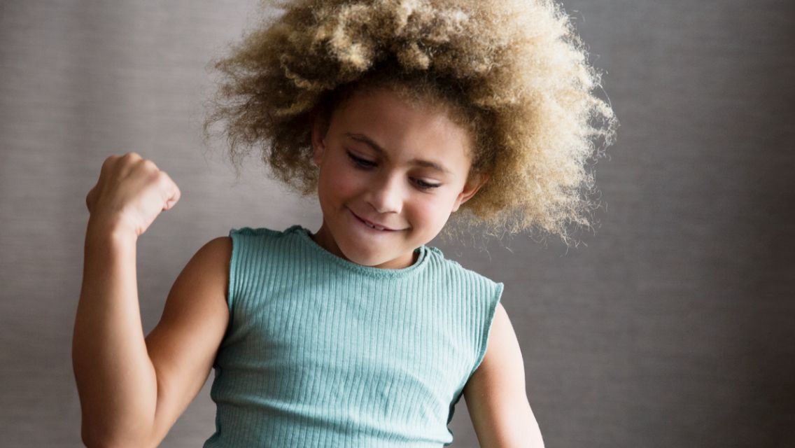 Child grinning with fist in the air