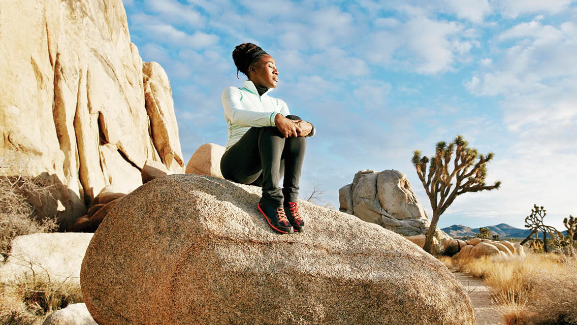 a woman rests on a larger boulder