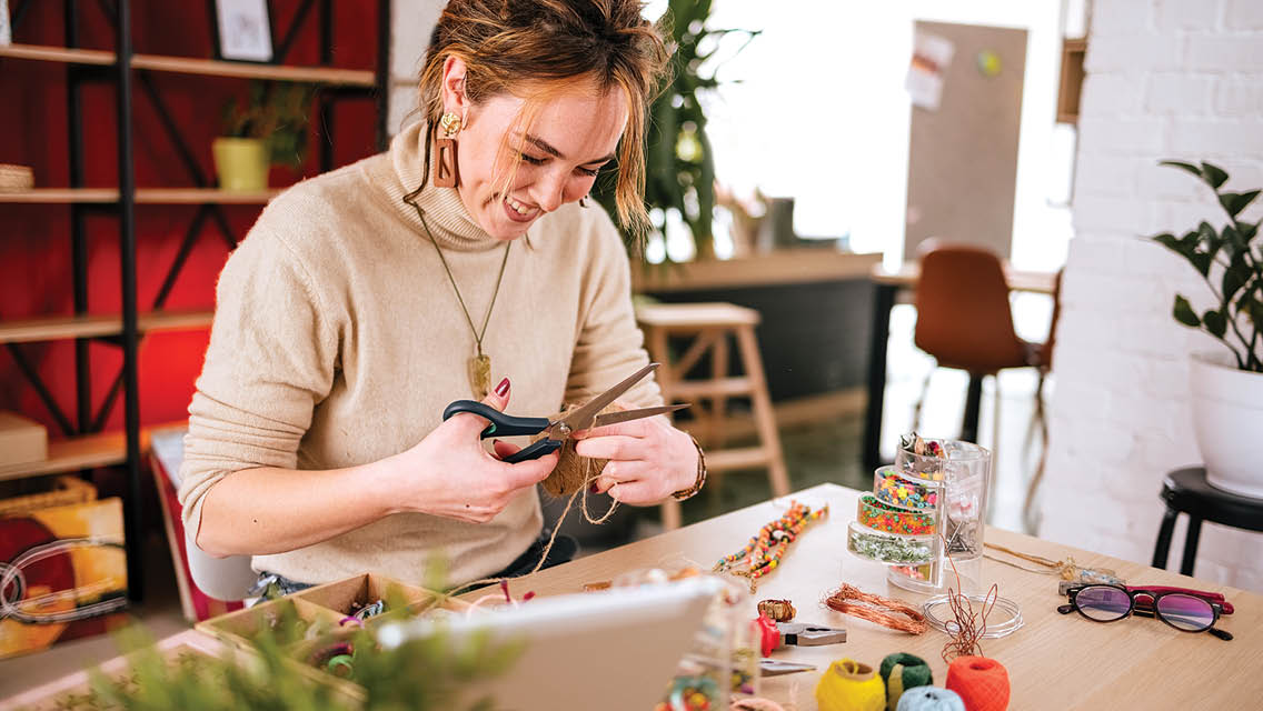a woman smiles while doing craft work