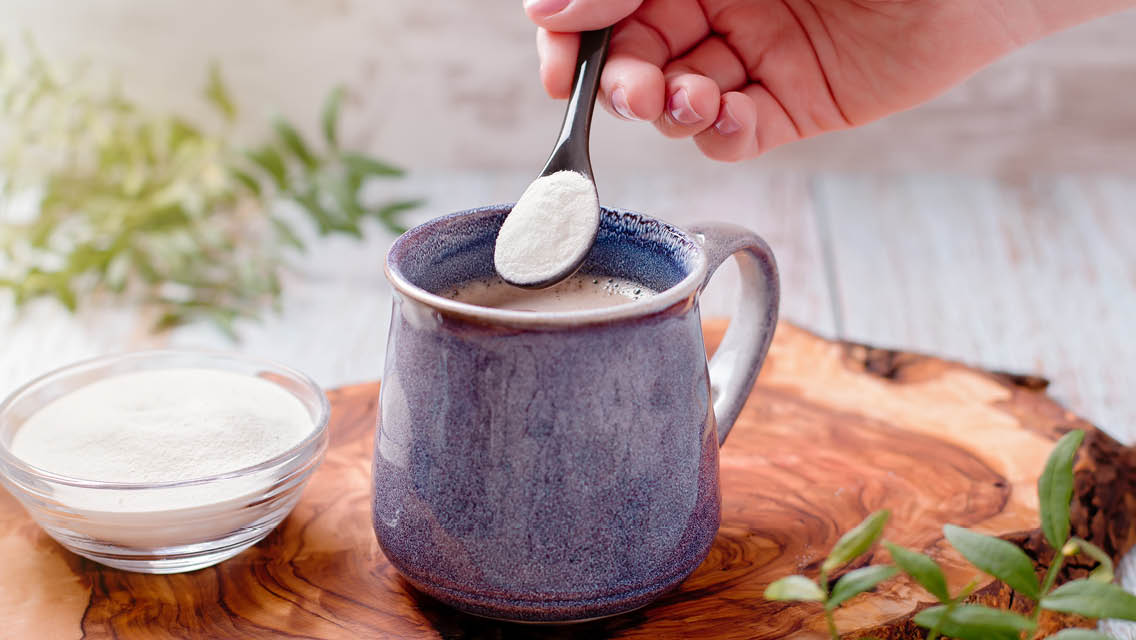 a person scoops collagen into a beverage