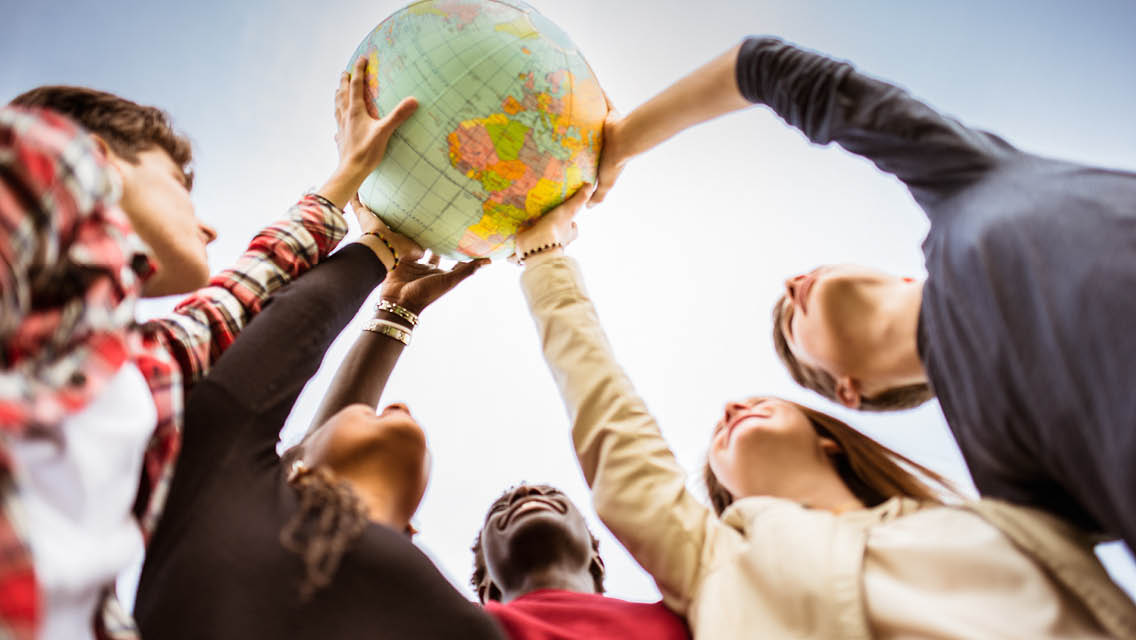 a group of people hold a globe