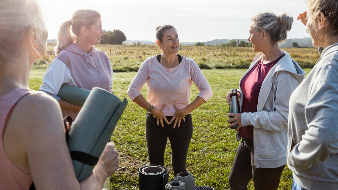 a woman holds her hands over the front of her pelvis while people watch