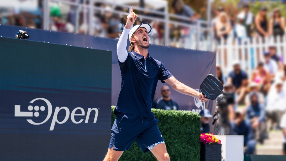 A pickleball player raising his paddle in the air at a tournament