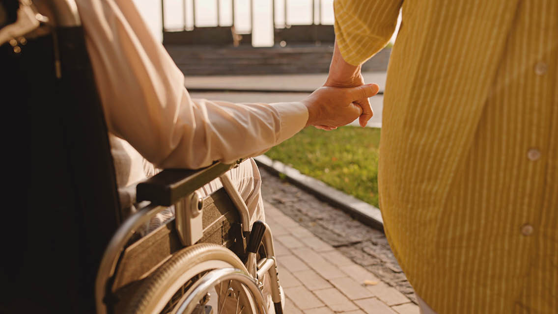 a person walks with a person in a wheel chair