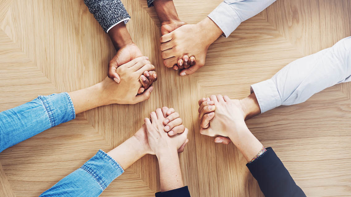 overhead image of 4 people holding hands