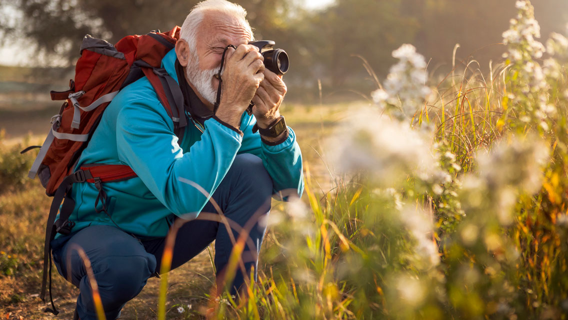 a senior man takes a photo while hiking