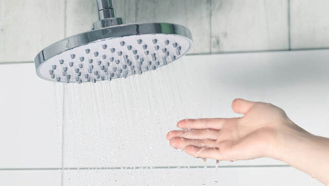 a hand catches water under a showerhead