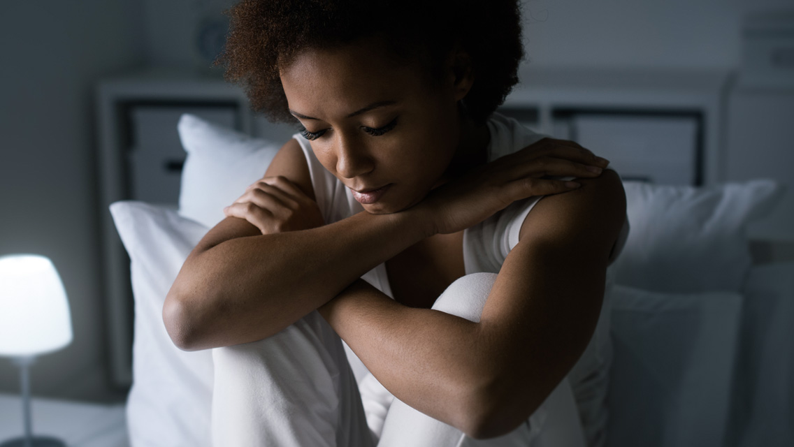 a woman sits in her bed thinking about stressful situations