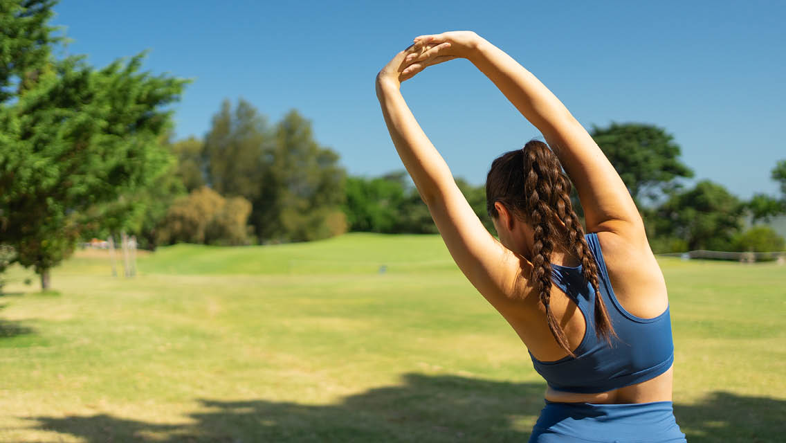 a woman stretches in a park