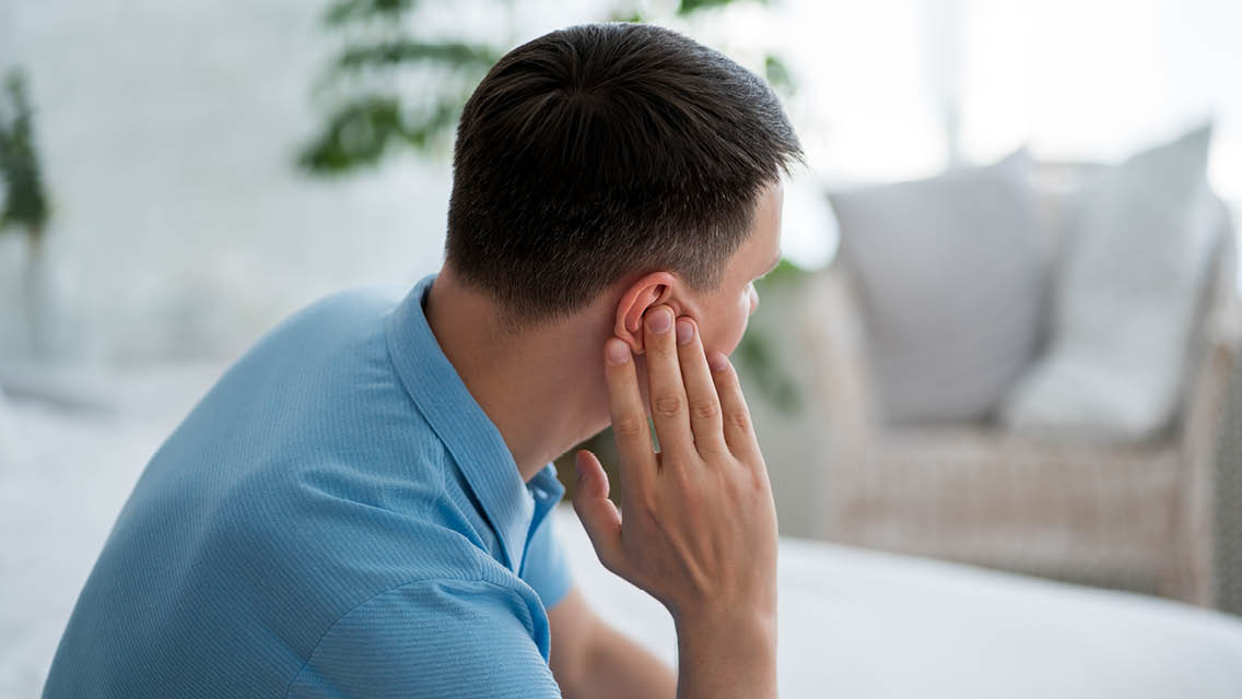 a man holds his ear as though their is ringing in it