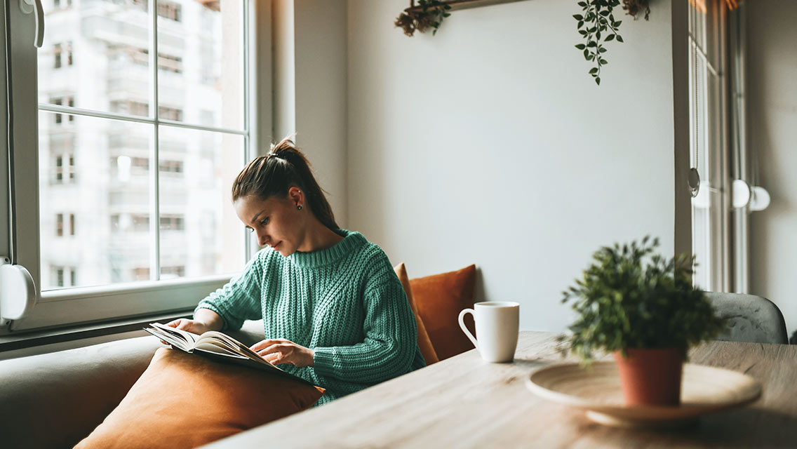 Woman reading a book and drinking coffee