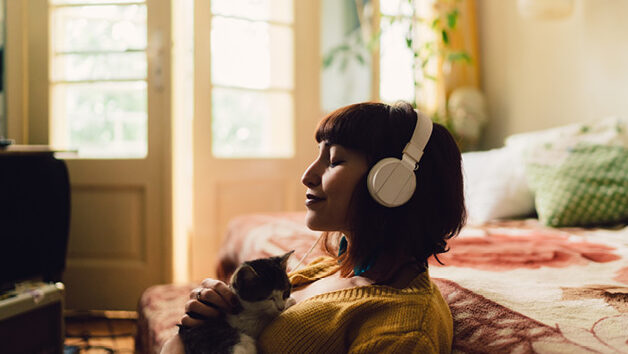 Woman listening to headphones and holding kitten