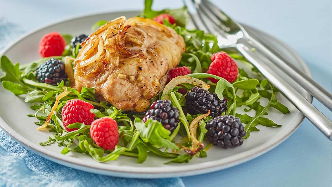 chicken on a bed of greens with berries