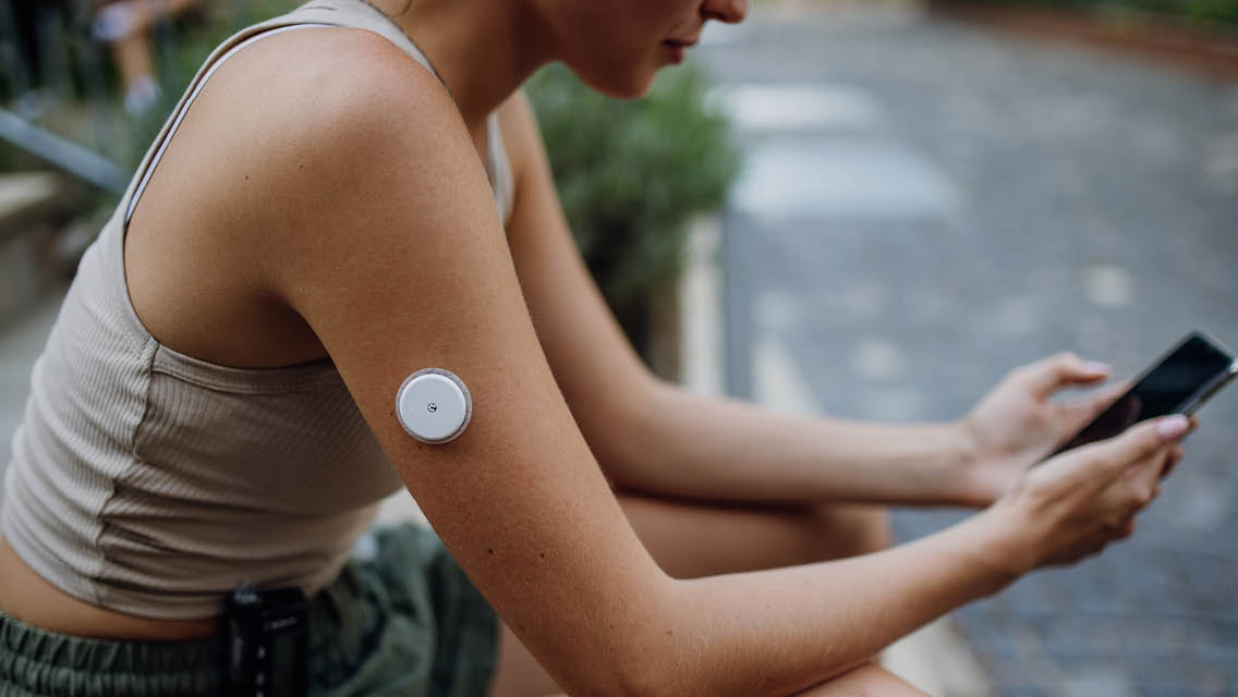 a woman wears a glucose monitor