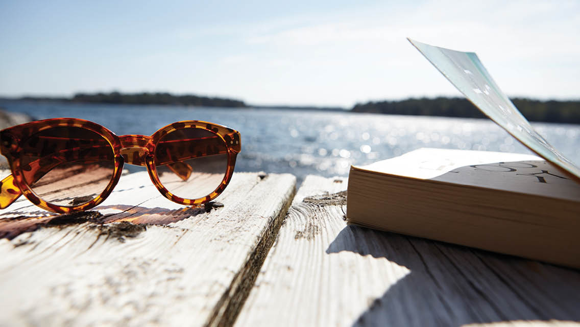 a book and suglasses sit on a dock
