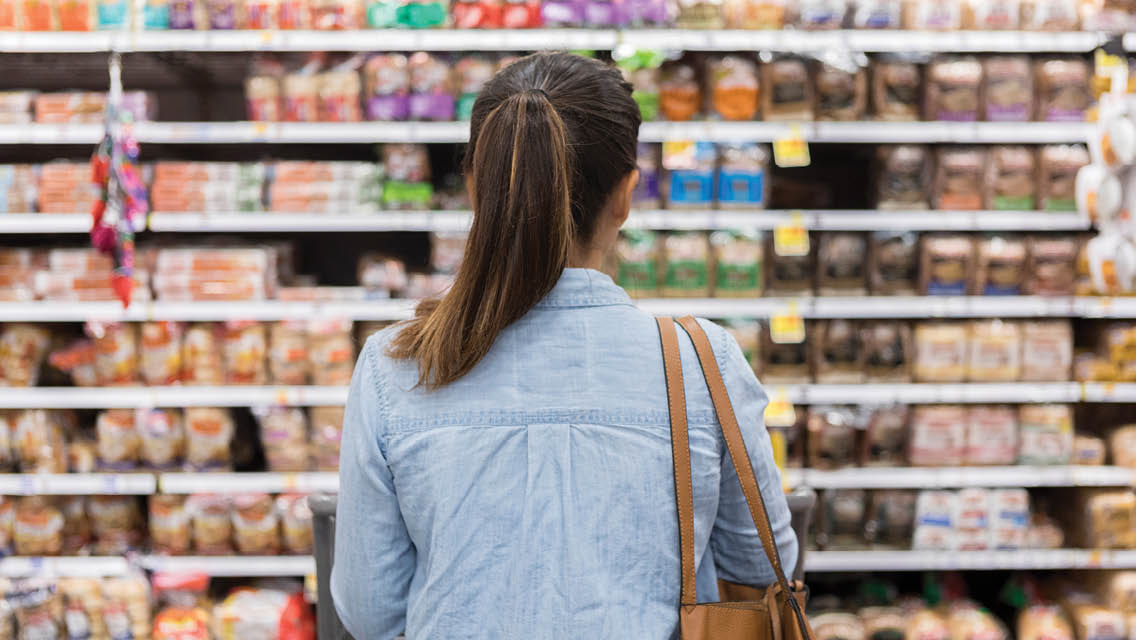 a woman looks at a wall of food in a grocery store